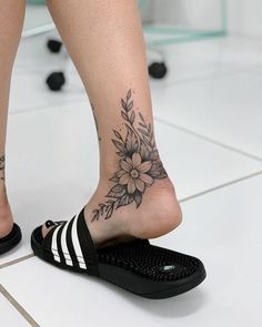 a woman's foot with flowers and stripes on the bottom of her shoe, while she is wearing black sandals