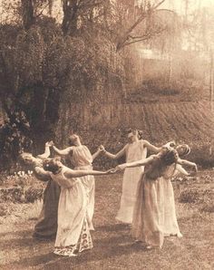 four women in long dresses holding hands with each other