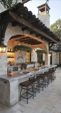 an outdoor kitchen with lots of counter space and lights hanging from the roof over it