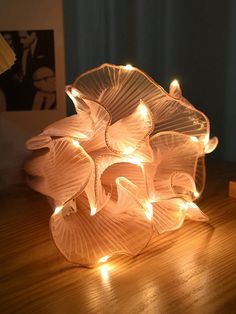 a glass vase sitting on top of a wooden table next to a lamp that is turned on