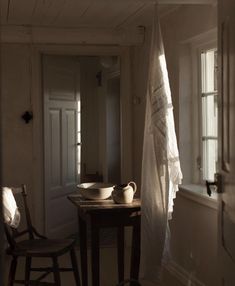 a table with two bowls on it in front of a window and a curtain hanging from the ceiling