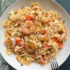 pasta with shrimp and tomatoes in a white bowl next to a fork on a table