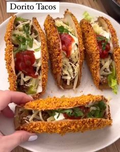 a plate with four tacos on it, one is cut in half and the other has toppings