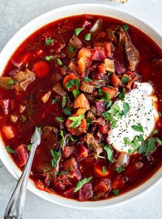 a bowl of soup with meat, potatoes and sour cream