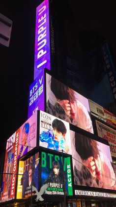 a very tall building with lots of billboards on it's sides at night