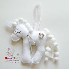 a white stuffed animal hanging from a string on a wall next to some beads and a bow