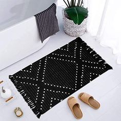 a black and white bathroom rug with slippers on the floor next to a bathtub