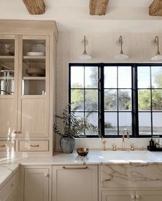 a kitchen with marble counter tops and wooden beams on the ceiling, along with large windows