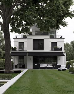 a large white house sitting on top of a lush green field next to a tree