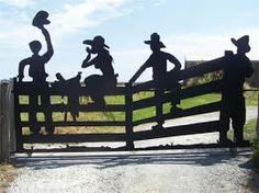 the silhouettes of cowboys are on top of a wooden fence with a cowboy's hat hanging from it