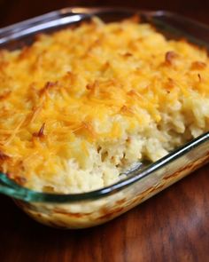 a casserole dish with cheese and potatoes in it on a wooden table top