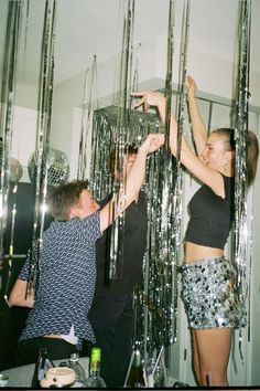 two people reaching up to grab something from the ceiling in front of them with their hands