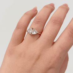 a woman's hand with a diamond ring on top of her left hand,