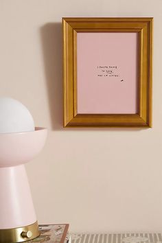 a pink lamp next to a gold framed art print