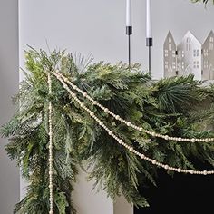 a christmas mantle decorated with greenery and candles