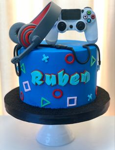 a blue cake with video game controllers on top and the word ruben spelled out