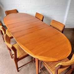 a large wooden table surrounded by chairs and a brick wall in an office setting with concrete flooring