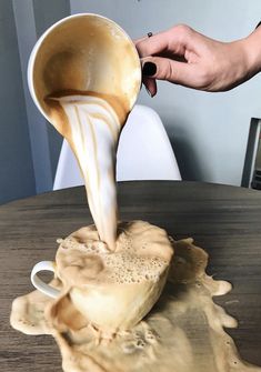 someone is pouring something into a bowl on top of a table