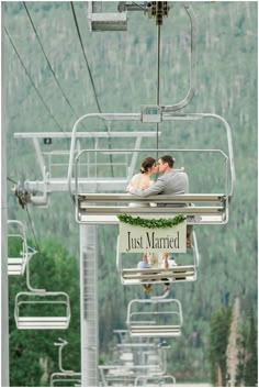 a bride and groom are kissing on the ski lift at just married, in front of a mountain