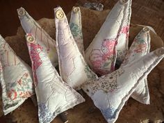 four decorative pillows sitting on top of a piece of wood with buttons in the middle