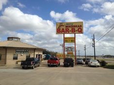 cars parked in front of a bar - b - q restaurant