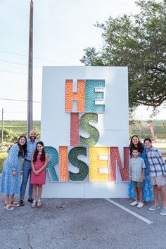 a group of people standing in front of a sign that says he is risen