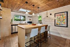 a kitchen with wood flooring and white chairs next to an island in the middle