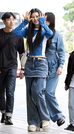 two people walking down the street with one person covering their eyes and holding her hands up