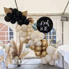 there is a balloon arch made out of balloons and other decorations on the table in front of a white tent