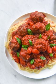 spaghetti and meatballs with tomato sauce on a white plate