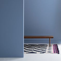 a blue room with a bench and rug on the floor