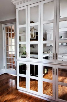 a kitchen with white cabinets and wood floors