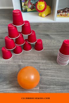 an orange ball and some red cups on the floor