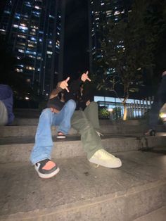 two people sitting on steps with their hands in the air and one person pointing at something