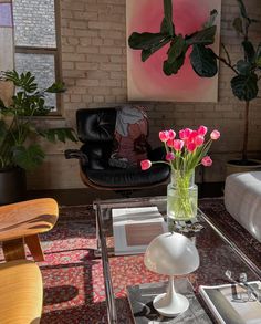 a living room filled with furniture and flowers on top of a glass table in front of a brick wall