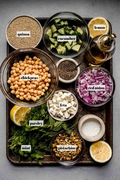 the ingredients for this salad are arranged in separate bowls on a serving tray, including lemons, cucumbers, chickpeas, red onions and parsley