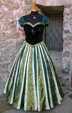 a green and white dress on display in front of a stone wall with a black top