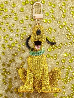 a yellow dog keychain with a green collar and leash hanging from it's mouth