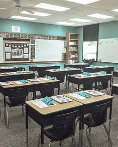 an empty classroom with desks and chairs in front of a chalkboard on the wall