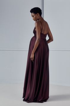 a woman in a long purple dress is looking down at the back of her gown