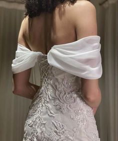 the back of a woman's wedding dress, with white fabric on her shoulders