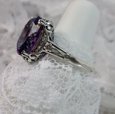 "Natural Purple Amethyst Ring Description Edward Design#70 (smaller version) MADE TO ORDER Inspired by Edwardian jewelry of the early 1900s, I now offer this lovely Antique reproduction ring in sterling silver. This gorgeous ring is set with a stunning 3.32ct Natural purple amethyst gemstone. This genuine amethyst has excellent color and clarity. The oval cut amethyst is 12mm (1/2th of an inch) Long by 10mm Wide (3/8th\"). The ring sits 6mm off the finger. The inside of the band s marked 925 for Oval Amethyst Ring With Diamond Cut, Oval Diamond Cut Amethyst Ring, Fine Jewelry Amethyst Ring With Diamond Cut, Fine Jewelry Diamond Cut Oval Amethyst Ring, Fine Jewelry Oval Amethyst Ring With Diamond Cut, Oval Amethyst Ring With Filigree Detail, Oval Amethyst Filigree Ring For Wedding, Ornate Oval Amethyst Ring, Oval Amethyst Ring With Intricate Design