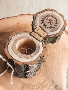 a wooden ring holder with an engraved initials on the front and side, sitting on top of a piece of wood