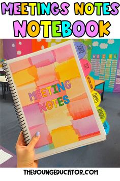 a person holding up a notebook with the words meeting notes on it in front of them