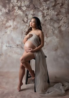 a pregnant woman sitting on a chair in front of a painting