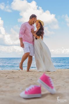 a man and woman standing on top of a sandy beach