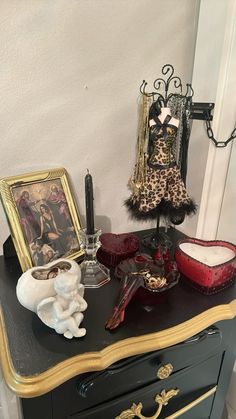 a black dresser with an ornate gold trimming and some pictures on the top shelf