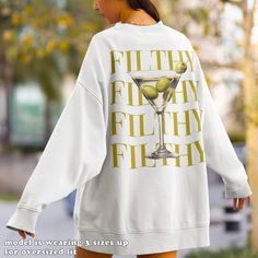 Indulge in the sophisticated allure of our Filthy Martini Sweatshirt--a perfect gift for yourself or Dirty Martini lover in your life. This Martini Cocktail Pullover, with its preppy crewneck style, is the ultimate 'Tini Time' sweater, making it a delightful and stylish gift for her, whether she's your wife, girlfriend or simply a cherished friend. - Fit -  Our shirts are super soft and comfy with a regular unisex fit. Want that extra oversized feel? Just check out the sizing chart image and go up 2-3 sizes for the perfect laid-back look! -Unique Designs Inspired By You-  Our designs are like the punchline to this amazing adventure we call life. Imagined by our hilariously talented artist and made just for you in our tiny slice of paradise right here in Sunny Florida - because laughter is Preppy Crewneck, Mother In Law Birthday, Gift Bachelorette Party, Bachelorette Party Shirt, Sweater Preppy, Crewneck Style, Dirty Martini, Martini Cocktail, Style Preppy