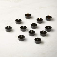 many black candles are arranged on a white surface