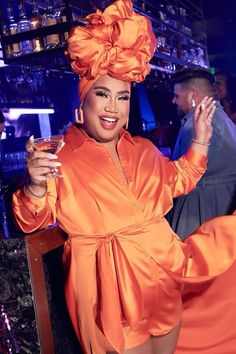 a woman in an orange outfit holding a drink